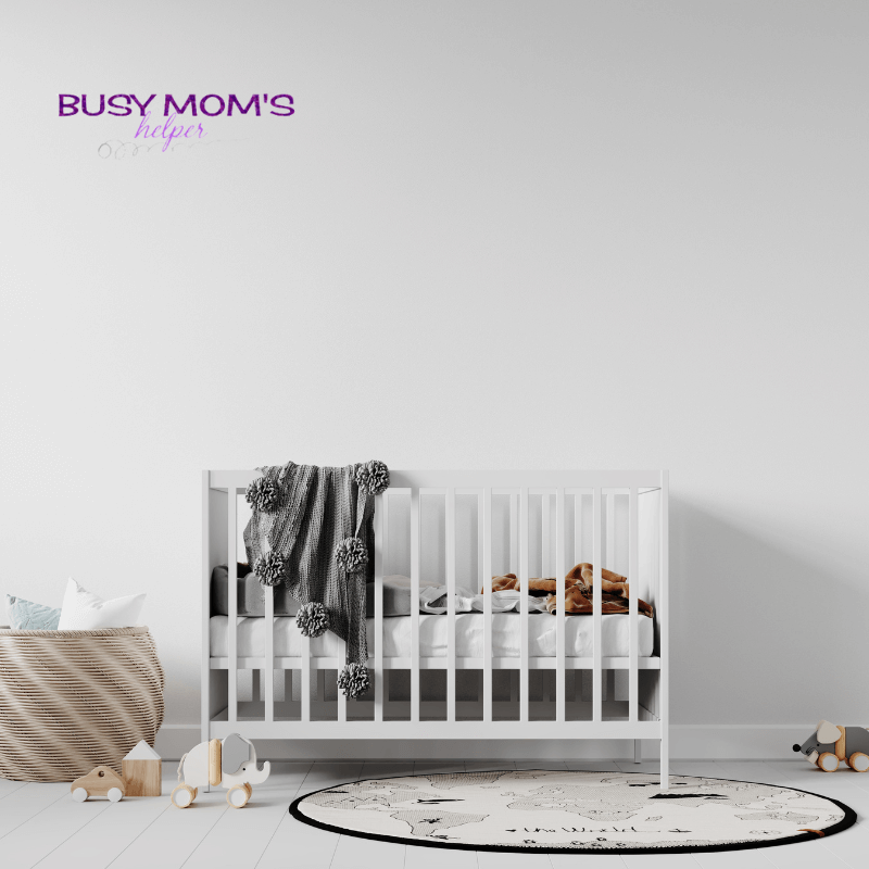 photo of a white crib in a white room with baby toys. 