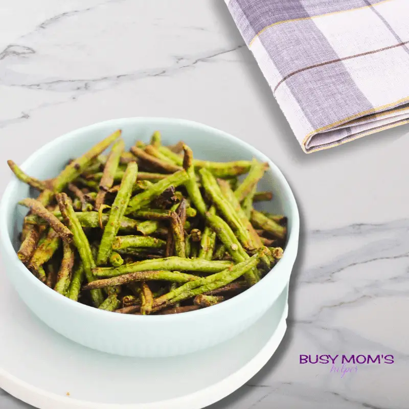 air fryer green beans in a white bowl on a marble counter top