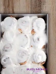 cinnamon rolls with cream cheese frosting on a wood table